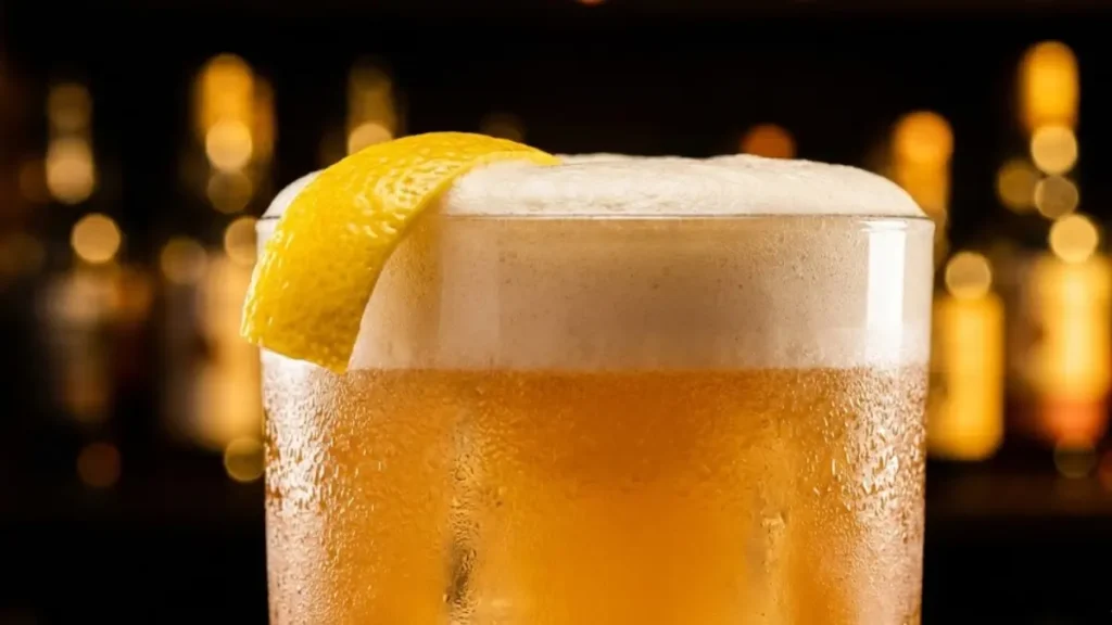 Best Amaretto Sour Recipe: Easy, Smooth & Perfect Every Time! 1 Close-up Amaretto Sour with thick foam and lemon twist, glowing under warm bar lights. - Amaretto Sour Recipe