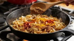 Moroccan Meatballs Recipe – Juicy, Spiced & Simmered in Rich Tomato Sauce 7 Spices being added to sautéed onions in a pan for moroccan meatballs sauce