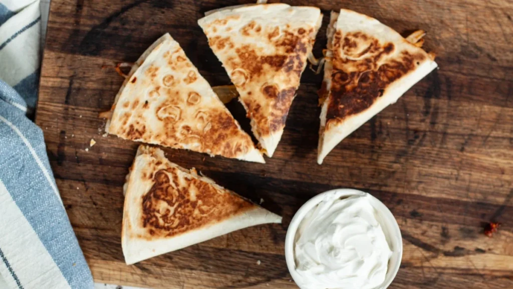 Chipotle Quesadilla: Calories, Nutrition (Ultimate 2025 Guide) 1 Chipotle chicken quesadilla served with sour cream, salsa, and Monterey Jack cheese – crispy, melty, restaurant-style quesadilla.