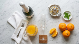 Classic Mimosa Recipe – The Perfect Brunch Cocktail in 5 Minutes 3 Mimosa ingredients including champagne, fresh oranges, and orange juice on a kitchen counter